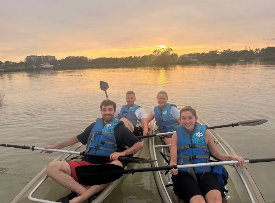 Sunset kayak tour guests paddling clear kayaks in the golden hour glow on Longboat Key